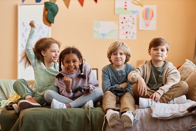 Zwei kleine Mädchen und Jungen beim gemeinsamen Gamen.