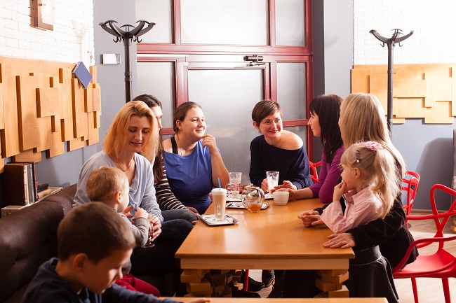 Eine Gruppe von Frauen trinkt etwas, Kinder sitzen in der Nähe.