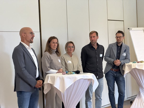 Eine Gruppe von 5 Personen steht zusammen an einem Stehtisch